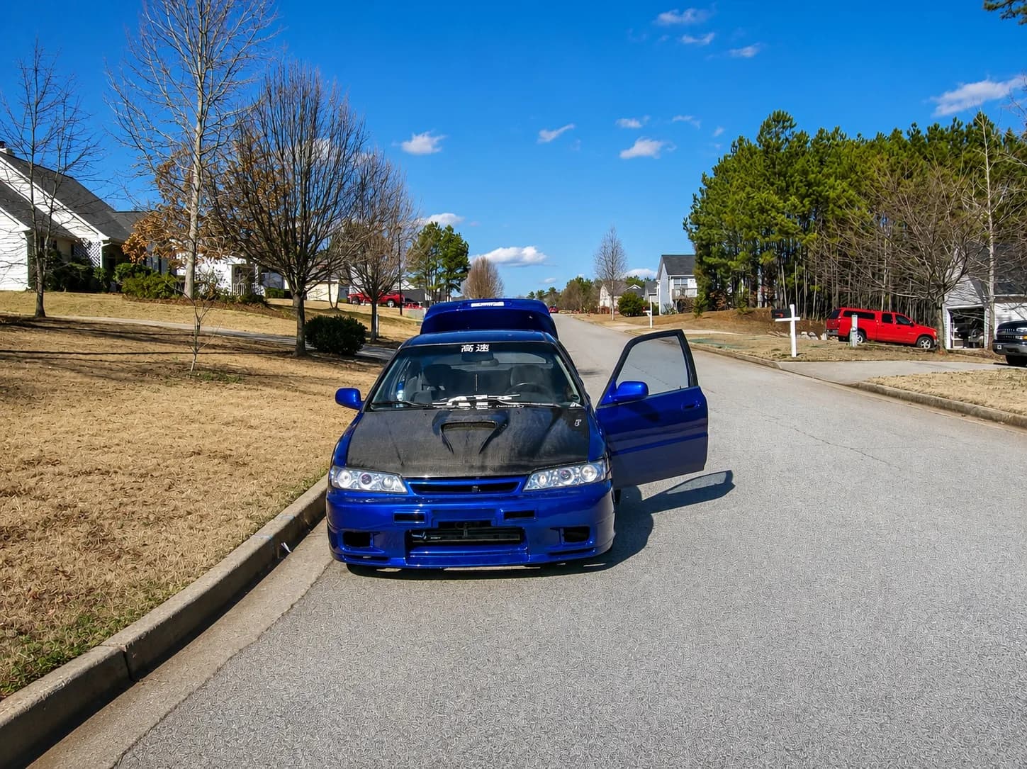 Blue customized Honda photographed from the front with its hood and driver door open